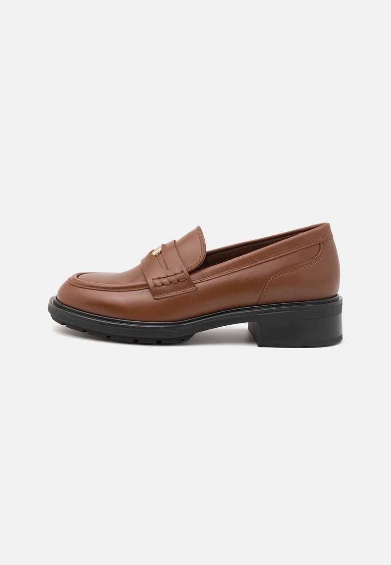 Mocassins en cuir marron avec un petit talon noir, présentant un design tissé sur la tige et un subtil accent de métal doré. Finition texturée.