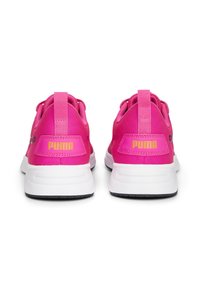 Des baskets Puma rose vif vues de l'arrière, avec des semelles blanches et des logos Puma jaunes sur les languettes de talon.