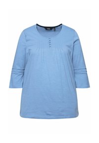 Helles blaues Oberteil mit dreiviertel Ärmeln, rundem Ausschnitt, Knopfdetail und plissiertem Design an der Vorderseite. Weicher Stoff mit subtiler Textur.
