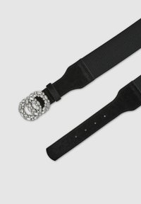 Cintura elastica nera con una fibbia rotonda multilivello in argento, caratterizzata da pietre trasparenti e scintillanti, e una fascia nera abbinata con fori di regolazione.