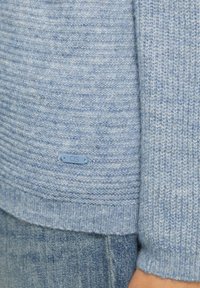 Lichtblauwe gebreide trui met een textuurpatroon, voorzien van een klein blauw QS-label aan de zoom en geribde manchetten.