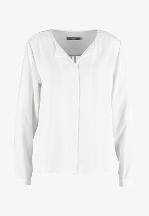 Balta ilgomis rankovėmis bluzonė, pagaminta iš lengvos medžiagos, su šiek tiek laisvu siluetu, turinti V formos iškirptę ir paslėptą priekinę mygtukų užsegimą.