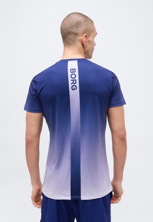 Hajvágott férfi, kék-fehér átmenetes rövid ujjú ingben, függőleges csíkkal és "BORG" felirattal a hátoldalon.