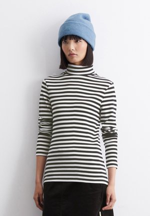 Maglietta a collo alto a righe in bianco e nero, caratterizzata da maniche lunghe e una texture a coste, abbinata a un berretto di maglia azzurro chiaro.