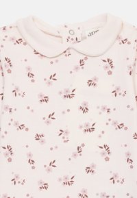 Tutina di cotone rosa pallido con colletto, chiusura a pressione e motivo floreale in rosa scuro e marrone con foglie sparse.
