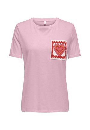 T-shirt rose clair à manches courtes avec un patch en crochet sur la poitrine représentant un cœur rouge et orange encadré d'une bordure en zigzag rouge.