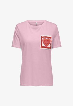 T-shirt rose clair à manches courtes avec un patch en crochet sur la poitrine représentant un cœur rouge et orange encadré d'une bordure en zigzag rouge.