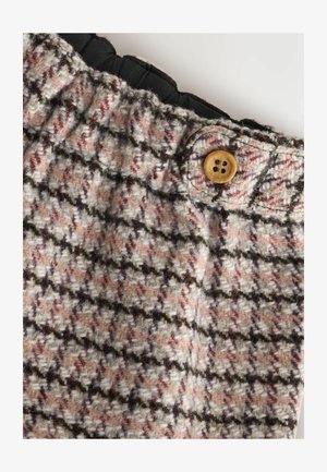 Volneno blago v roza in bež houndstooth vzorcu, ki vključuje črn elastik za pas in okroglo leseno gumbno zapiranje.