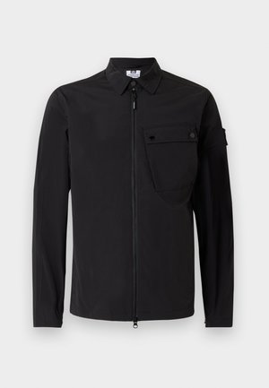 Black lightweight jacket with a zip front, pointed collar, long sleeves, and a chest pocket featuring a snap button closure. Smooth texture.