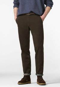 Bruine chinos met een slanke pasvorm, gemaakt van stevig katoen. Kenmerkt zich door opgerolde manchetten met een patroon. Gecombineerd met bruine suède enkellaarsjes.