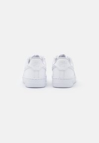 White Nike Air sneakers with padded collars, textured leather, rubber soles, and embossed branding details on the heel and side.