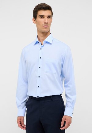 Himmelblaues Langarmhemd mit spitzem Kragen, dunklen Knöpfen und einer einzelnen Brusttasche. Glattes Material mit strukturiertem Schnitt.