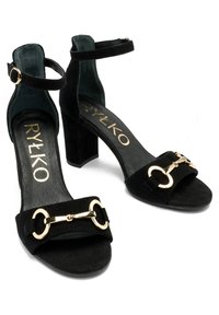 Des sandales à talons hauts en suède noir avec une bride de cheville et des accents en métal doré à l'avant, dotées d'une semelle intérieure texturée et d'un talon bloc.