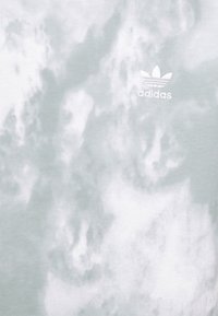 Svetle šedé tričko s vzorem mraků, vyrobené z měkké látky, s vyšitým bílým logem Adidas blízko výstřihu.