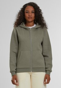 Sudadera verde con cremallera hecha de tela suave, con capucha ajustable, bolsillos frontales y puños y dobladillo acanalados.