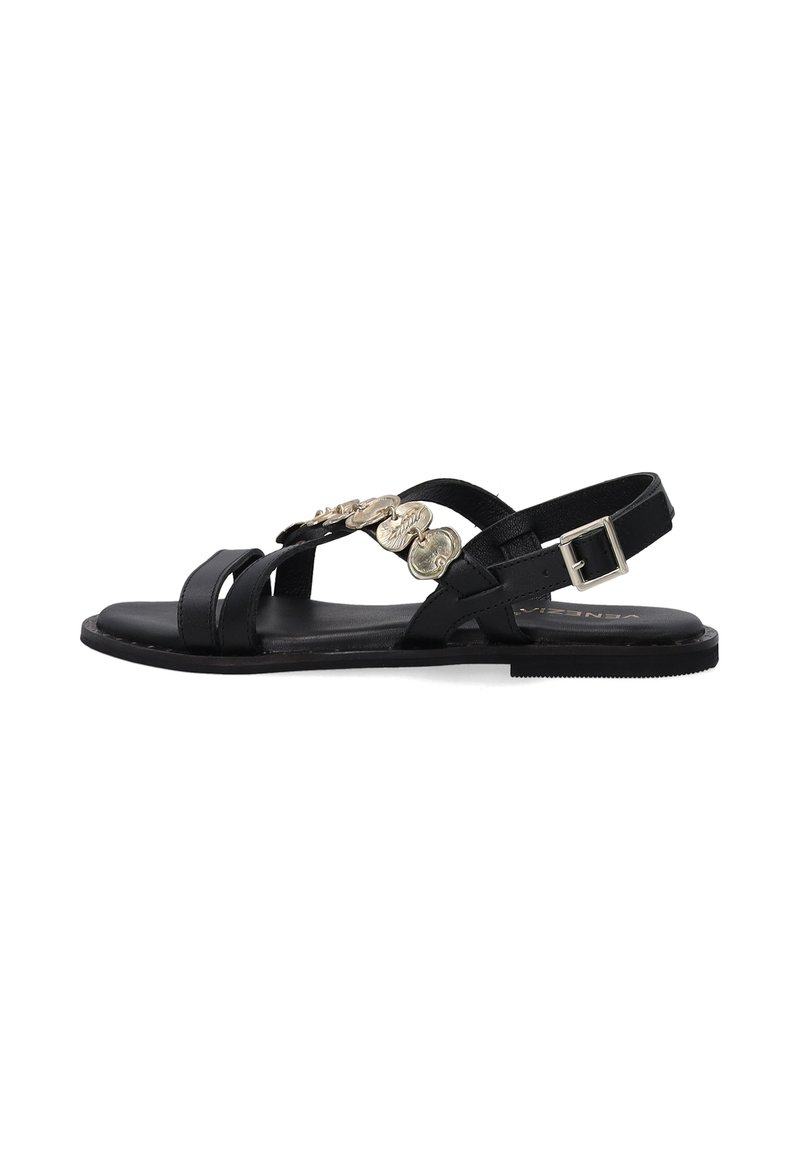 Schwarze flache Sandalen mit einem Riemen-Design, das dekorative metallische Akzente und einen Schnallenverschluss am Knöchelriemen aufweist.