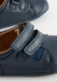 Dunkelblaue Lederschuhe mit zwei Klettverschlüssen, strukturierten Akzenten und einer glatten Oberfläche. Für Komfort entworfen mit einem weichen Innenfutter.