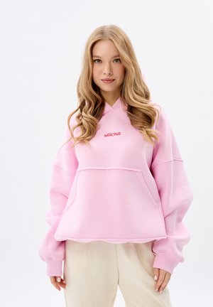 Felpa oversized rosa con tasca frontale e logo "MIRONS" in rosso. Presenta una vestibilità rilassata, maniche larghe e un tessuto texturizzato.