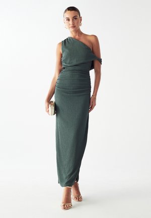 Einrichtung mit einem schulterfreien, grünen Kleid aus strukturiertem Stoff; gerafftes Design, figurbetonte Silhouette und knielange Länge. Mit einer Clutch accessorisiert.