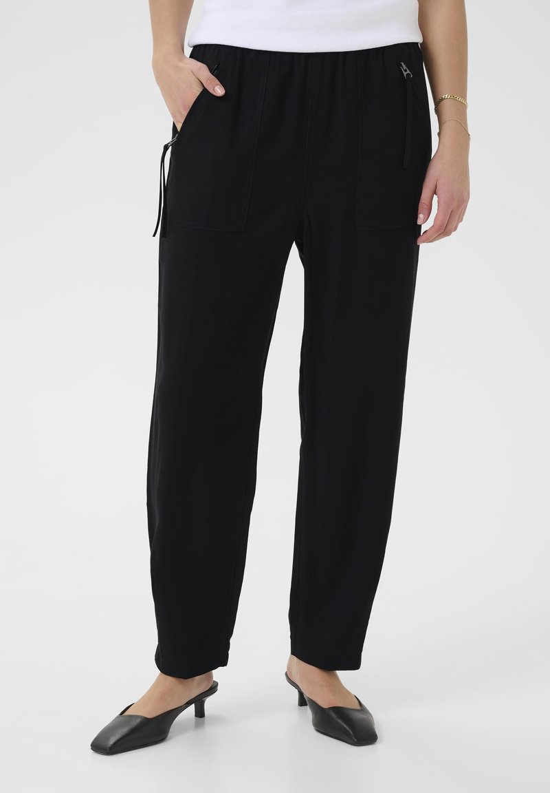 Pantaloni neri con vita elastica, dotati di due tasche frontali e dettagli con coulisse. Realizzati in un materiale liscio, présentano gambe affusolate e una vestibilità rilassata.