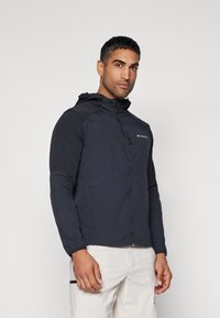 Men's dark gray Columbia jacket with a hood, full zip, and elastic cuffs, featuring a logo on the left chest and a lightweight design.