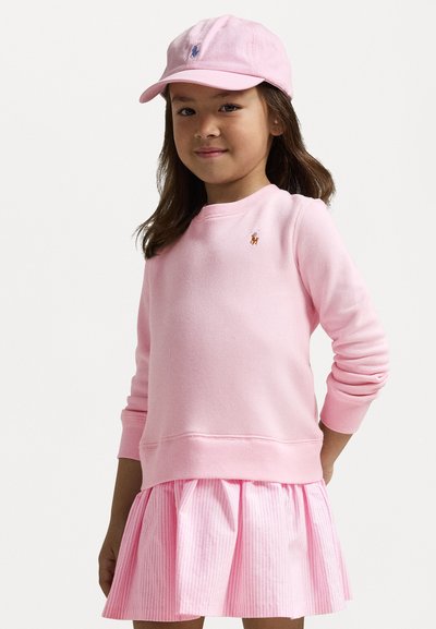 Heled roosa dressipluus ribitud varrukatega, mis on sobitatud roosa triibulise kleidiga, millel on sama värvi müts, mõlemad logo aktsentidega.