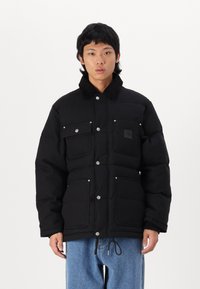 Schwarze Steppjacke mit hohem Kragen, Druckknöpfen und vier Vorderaschen. Hergestellt aus glattem Material mit strukturierter Oberfläche.