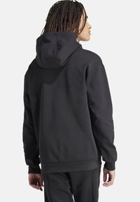 Zwarte hoodie met een ontspannen pasvorm, geribde manchetten en zoom. Gladde stofstructuur, geen zichtbare logo's of patronen.