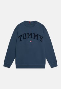 Tamno plavi dukserica od mješavine pamuka. Sadrži "TOMMY" u izbočenim slovima preko prednje strane, s malim logotipom uz rub.