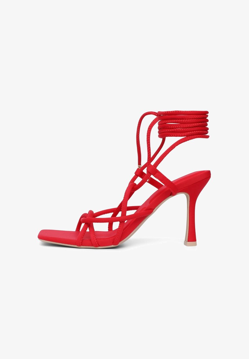 Rote High-Heel-Sandaletten mit dünnen, überkreuzten Riemen und einem gewickelten Knöcheldesign. Glatte Oberfläche mit einer quadratischen Zehenpartie und beiger Sohle.