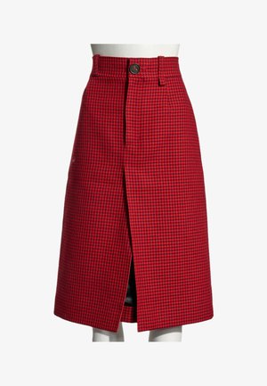 Jupe à carreaux pied-de-poule rouge et noire longueur genou avec une fente devant et un seul bouton visible à la taille sur un mannequin.