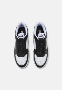 Ténis atléticos em preto e branco com parte superior em pele, caixa dos dedos perfurada, atacadores pretos e colarinho acolchoado. Apresenta o logo da Puma na língua.