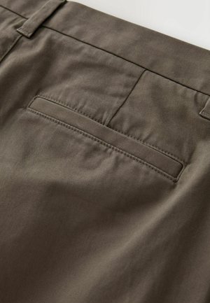 Rudos kelnės iš lygaus, tekstūruoto audinio. Yra užpakalinis kišenė su tvarkingu, tiesiu siūlė ir be matomų detalių ar puošmenų.