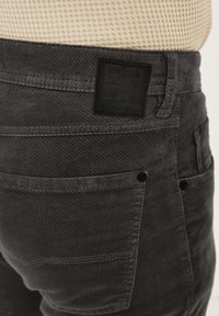 Dunkelgraue Denim-Hose mit strukturierter Oberfläche, ausgestattet mit Gesäßtaschen und einem schwarzen Lederetikett mit der Aufschrift "REDPOINT DENIM".