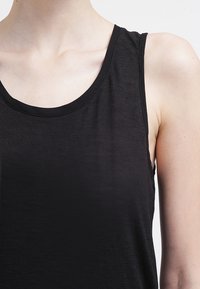 Top senza maniche di colore nero con scollatura rotonda, realizzato in tessuto leggero, con una texture liscia e cuciture minime per un design pulito.