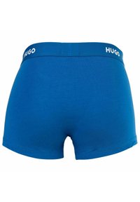 Blaue Baumwoll-Boxershorts mit eng anliegender Passform und einem weißen "HUGO"-Logo auf dem elastischen Bund, mit glatter Textur und ohne Muster.