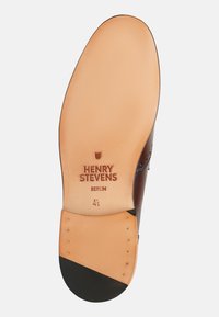 Sola di scarpa in pelle marrone con il marchio inciso "HENRY STEVENS BERLIN." Presenta una superficie liscia color tan e un copri tacco in gomma nera.