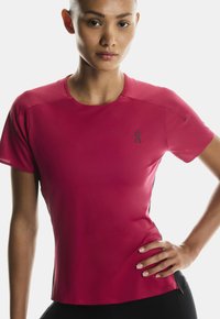 Krátký rukáv sportovní tričko v živé růžové barvě, vyrobené z lehké, vlhkosti odvádějící látky s kulatým výstřihem a decentním logem.