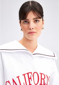 White sweatshirt featuring a broad, striking sailor collar, red "CALIFORNIA" text, and contrasting striped detailing on the collar.