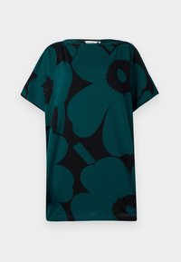 Teal oversized majica s črnim cvetličnim vzorcem. Ima okroglo vratno odprtino in kratke rokave, izdelana iz mehkega, lahkega materiala.
