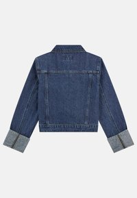 Jeansjacka i mörkblått, kort design med en bakre yok. Har vikta manschetter i ljusare denim och synliga sömnadsdetaljer.