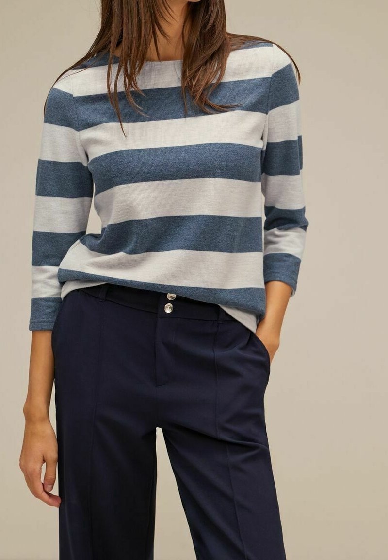 Blå och grå randig topp med trekvartsärmar, tillverkad av mjukt stickat tyg. Kombinerad med mörkblå skräddarsydda byxor med två knappar.