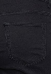 Sorte denim jeans med en baglomme med en syet kant, glat tekstur og en tætsiddende design. Ingen synlig branding eller udsmykninger.