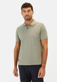 Grågrøn polo-shirt lavet af glat stof, med en placket med tre knapper og et lille logo på brystet. Bæres med mørke cargo shorts.