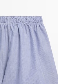 Tessuto a righe blu e bianco, con vita elasticizzata e texture arricciata, con linee verticali che percorrono l'intero tessuto.