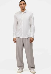 White long-sleeve button-up shirt paired with light gray wide-leg trousers and white sneakers, featuring a standard collar and front buttons.