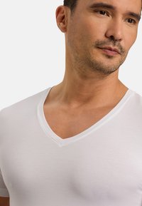 Biała koszulka V-neck z miękkiego materiału, charakteryzująca się gładką teksturą i dopasowanym krojem, z eleganckim dekoltem.