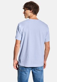 T-shirt en coton bleu clair à manches courtes et coupe décontractée. Texture lisse et col rond classique, vu de dos.