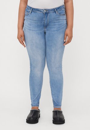 Light blue skinny jeans made of denim, featuring a high waist, subtle fading, and five-pocket design, paired with black clogs.