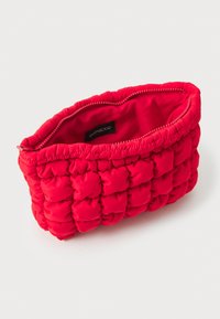 Borsa cosmetica rossa imbottita con un design a tessuto trapuntato, dotata di una chiusura con zip liscia e fodera in tessuto. Etichetta interna: “even&odd.”